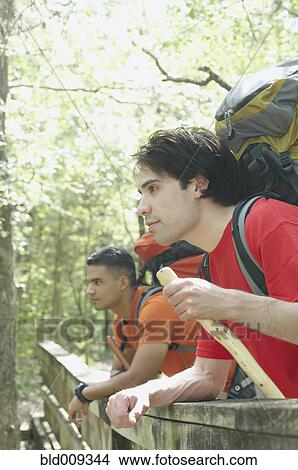 Picture - Two young men leaning on a forest railing. Fotosearch
