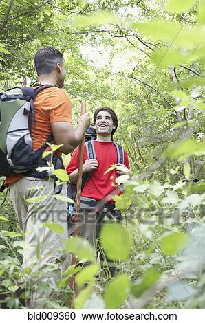 Stock Image - Two young men talking in a forest. Fotosearch