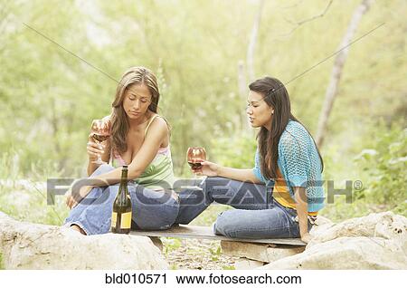 Two young women holding glasses of wine View Large Photo Image Stock Image - Two young women holding glasses of wine. Fotosearch