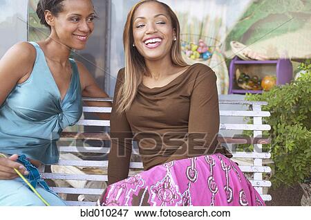 Stock Photo - Two young women sitting on a bench. Fotosearch