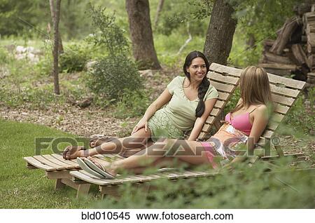 Stock Photography - Two young women sitting on lounge chairs. Fotosearch