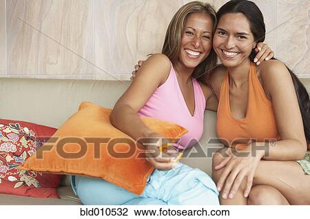 Two young women together on couch View Large Photo Image Stock Image - Two young women together on couch. Fotosearch
