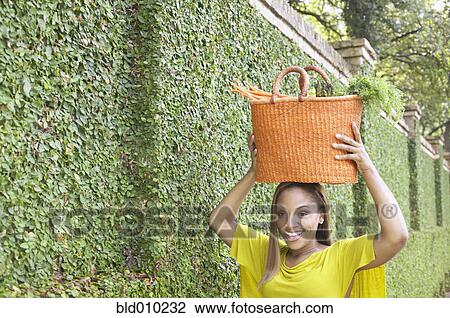 Woman holding a basket on her head View Large Photo Image Stock Image - Woman holding a basket on her head. Fotosearch