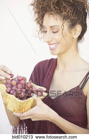 Stock Image - Woman holding a bowl of grapes. Fotosearch