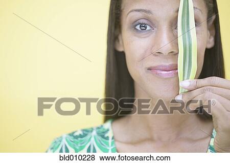 Stock Photo - Woman holding a leaf in front of eye. Fotosearch