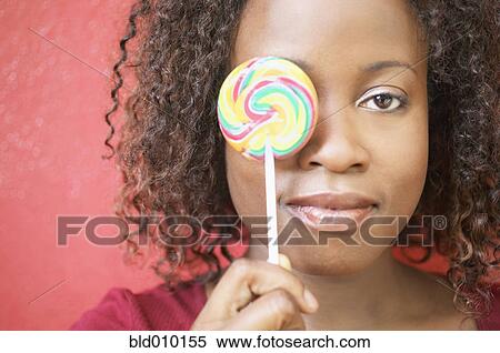 Woman holding lollipop in front of her eye View Large Photo Image Stock Photography - Woman holding lollipop in front of her eye. Fotosearch
