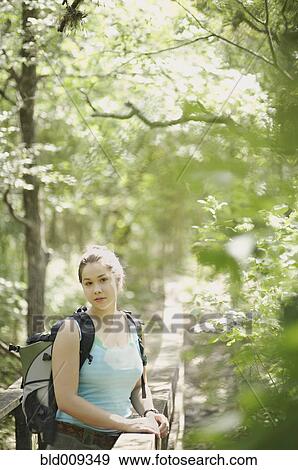 Stock Photo - Woman leaning against a forest railing. Fotosearch