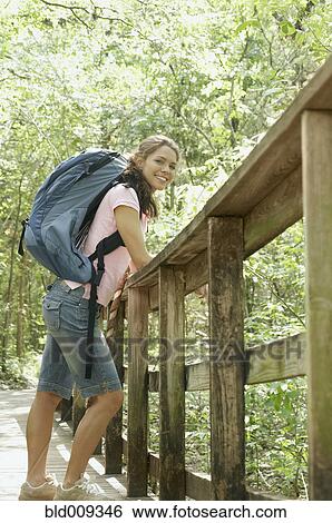 Stock Photograph - Woman leaning against a forest railing. Fotosearch