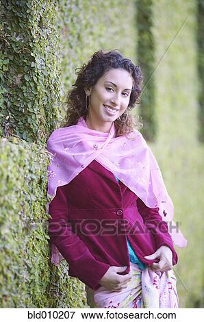 Stock Photo - Woman leaning against a hedge. Fotosearch