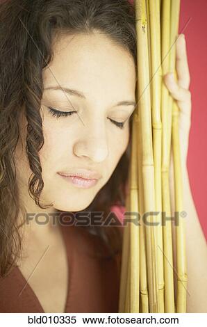 Stock Photography - Woman leaning against wooden sticks. Fotosearch