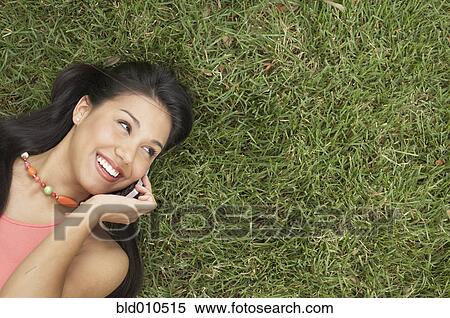 Woman lying on grass talking on mobile phone View Large Photo Image Stock Photography - Woman lying on grass talking on mobile phone. Fotosearch