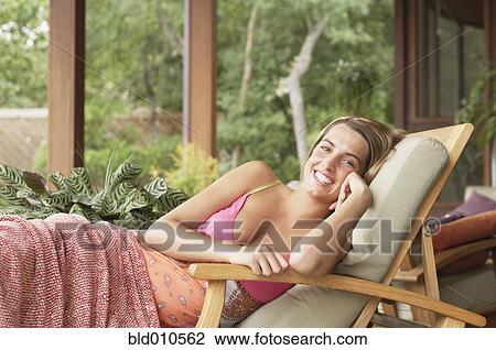 Stock Image - Woman lying on lounge chair outside. Fotosearch