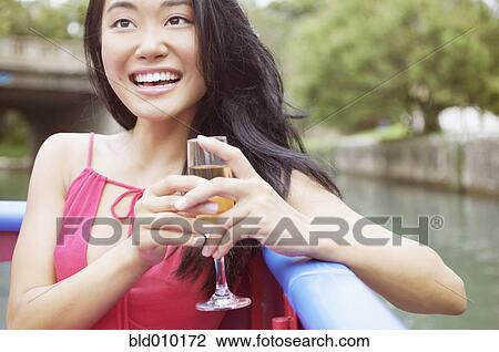 Stock Image - Woman on a boat holding a glass of wine. Fotosearch