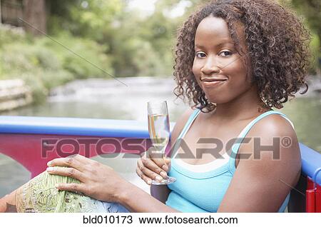Stock Image - Woman on a boat holding a glass of wine. Fotosearch