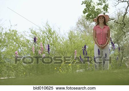Stock Photography - Woman standing in flower garden. Fotosearch
