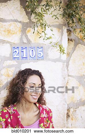 Stock Image - Woman standing in front of a stone wall. Fotosearch