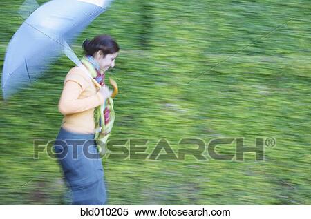 Stock Photography - Woman walking with an umbrella. Fotosearch