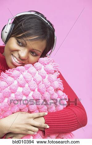 Picture - Woman with pillow wearing headphones. Fotosearch