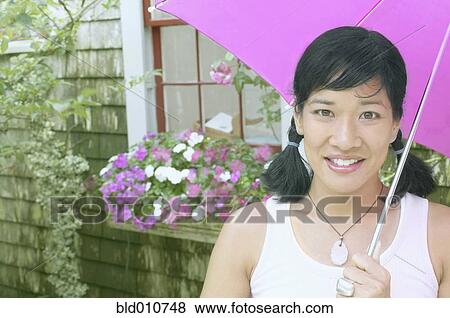 Stock Photo - Woman with umbrella next to house. Fotosearch