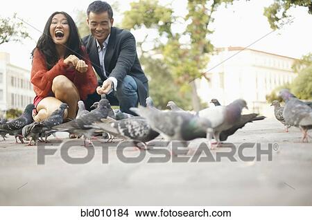 Young couple feeding pigeons View Large Photo Image Picture - Young couple feeding pigeons. Fotosearch