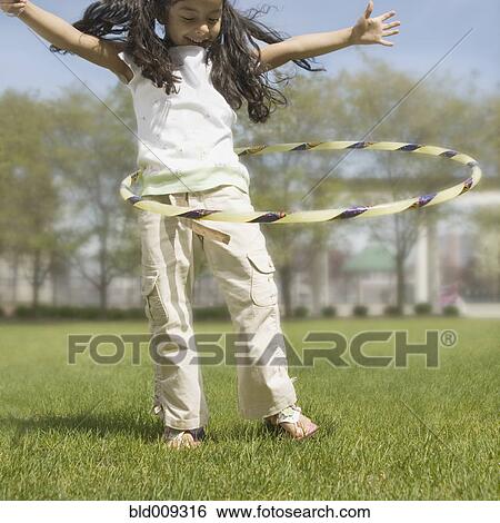 Young girl rotating a hula hoop View Large Photo Image Stock Photograph - Young girl rotating a hula hoop. Fotosearch