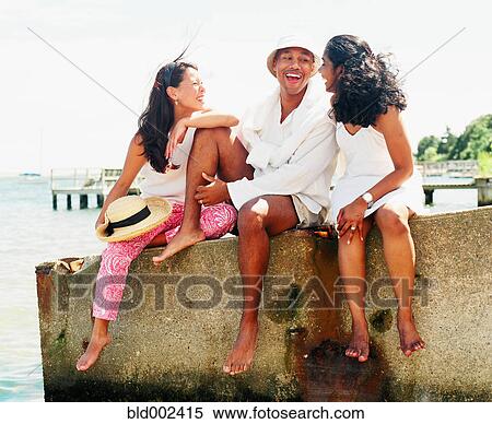 Stock Photography - Young man and women relaxing near shore. Fotosearch