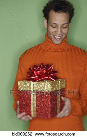Stock Image - Young man holding a gift. Fotosearch