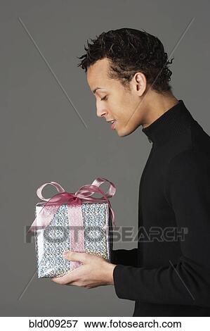 Stock Photo - Young man holding a gift. Fotosearch