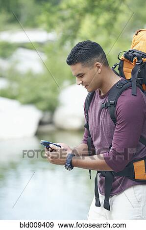 Young man holding a mobile phone View Large Photo Image Stock Photo - Young man holding a mobile phone. Fotosearch
