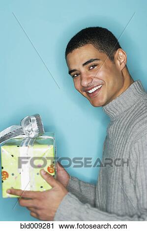 Stock Image - Young man holding gift. Fotosearch