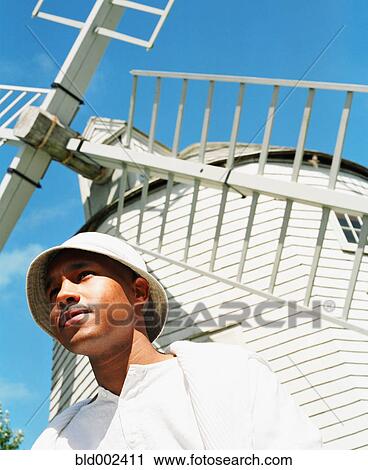Young man posing with windmill in background View Large Photo Image Stock Image - Young man posing with windmill in background. Fotosearch