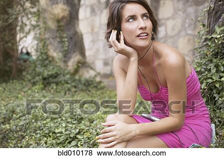 Stock Photo - Young sitting woman listening to music. Fotosearch