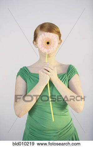 Stock Photo - Young woman covering her face with a flower. Fotosearch