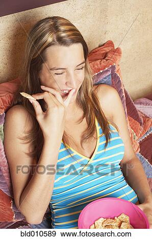 Stock Photo - Young woman eating crackers. Fotosearch