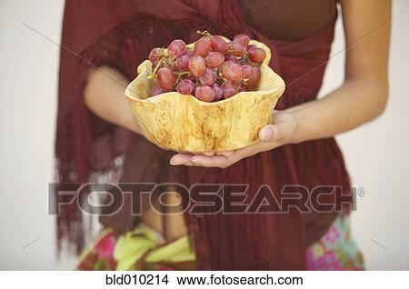 Picture - Young woman holding a bowl of grapes. Fotosearch