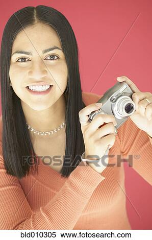 Young woman holding a camera View Large Photo Image Stock Photography - Young woman holding a camera. Fotosearch