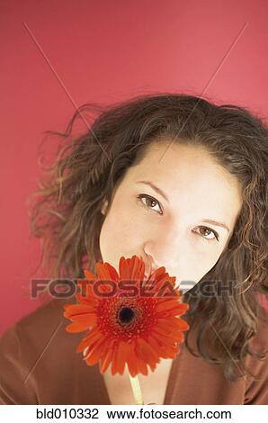 Stock Image - Young woman holding a flower. Fotosearch