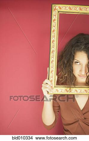 Picture - Young woman holding a picture frame. Fotosearch
