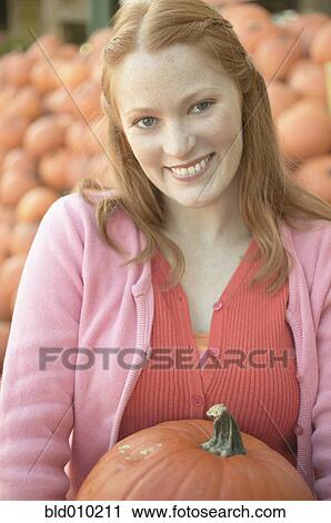 Young woman holding a pumpkin View Large Photo Image Stock Image - Young woman holding a pumpkin. Fotosearch