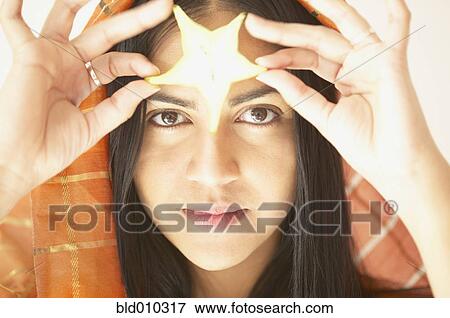 Young woman holding a star decoration View Large Photo Image Stock Photo - Young woman holding a star decoration. Fotosearch