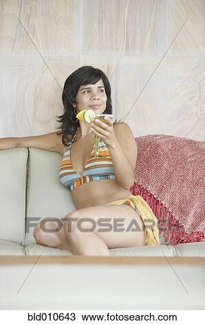 Stock Image - Young woman holding martini glass. Fotosearch