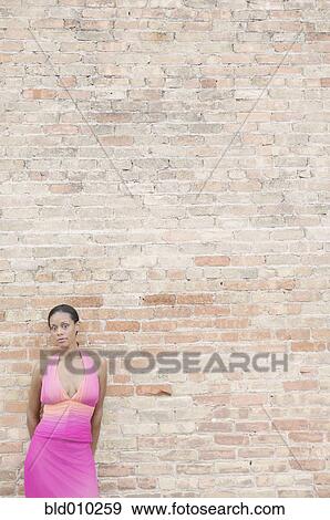 Young woman in front of a brick wall View Large Photo Image Stock Photo - Young woman in front of a brick wall. Fotosearch