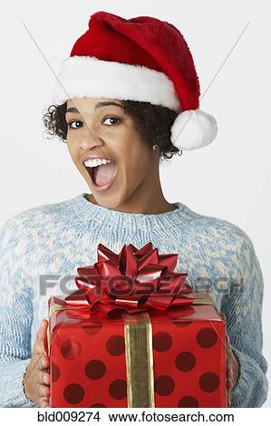 Picture - Young woman in Santa hat with gift. Fotosearch
