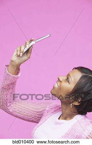 Stock Image - Young woman looking at mobile phone. Fotosearch