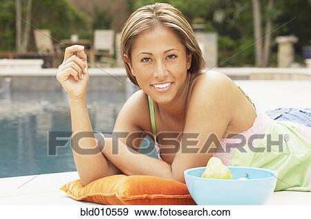 Stock Photo - Young woman lying beside swimming pool. Fotosearch