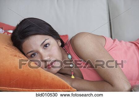 Young woman lying down on couch View Large Photo Image Stock Image - Young woman lying down on couch. Fotosearch