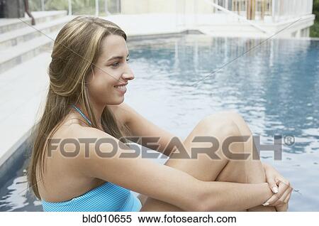 Young woman sitting at poolside View Large Photo Image Stock Photography - Young woman sitting at poolside. Fotosearch