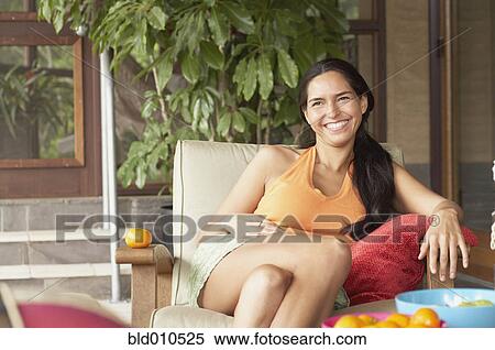 Stock Photography - Young woman sitting on a chair and smiling. Fotosearch