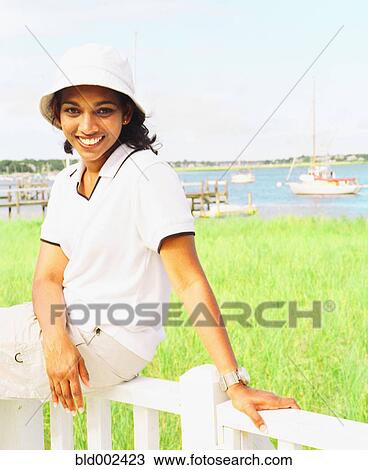 Young woman sitting on railing at waterfront View Large Photo Image Stock Image - Young woman sitting on railing at waterfront. Fotosearch