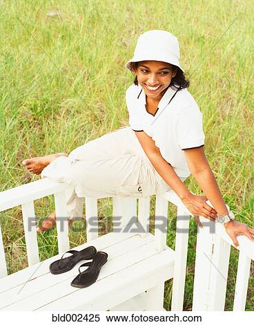 Young woman sitting on railing View Large Photo Image Stock Photography - Young woman sitting on railing. Fotosearch